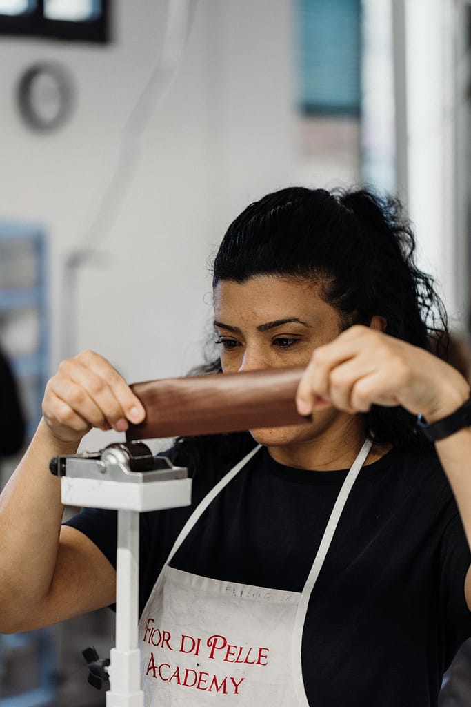 ragazza in laboratorio che sta lavorando la pelle con apposito macchinario
